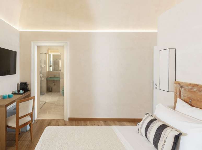 Ein hell eingerichtetes Hotelzimmer mit einem Bett, einem Schreibtisch und einem Blick in das Badezimmer.