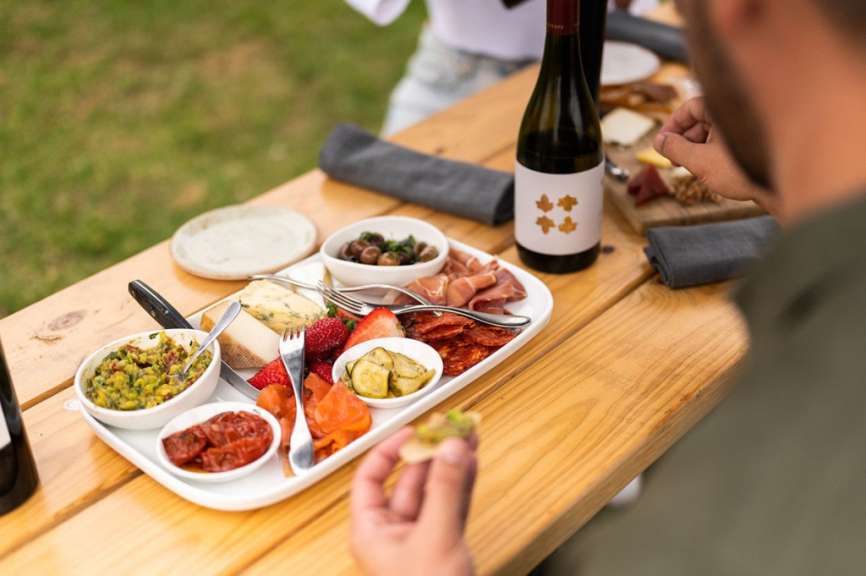 Ein Mann sitzt an einem Holztisch mit einem Teller mit Essen und einer Flasche Wein