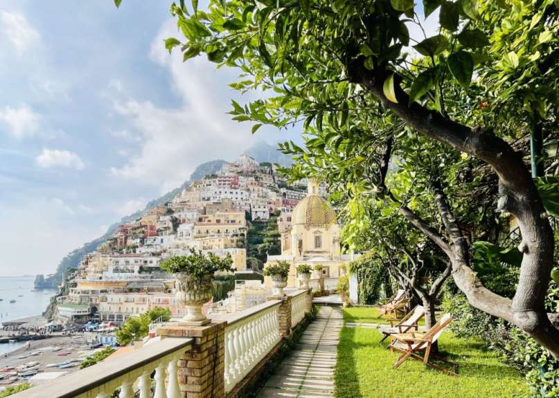 Ein Garten mit Bäumen und Stühlen und einer Kirche im Hintergrund