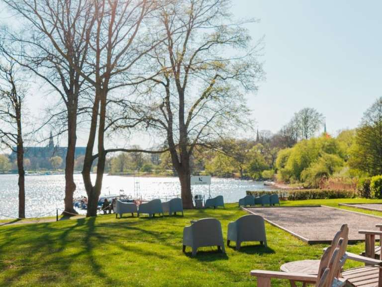 Eine Gruppe von Stühlen steht auf einer Wiese in der Nähe eines Sees