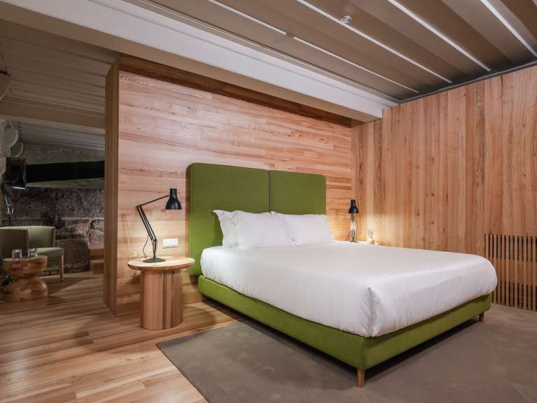 Ein Schlafzimmer mit Holzwänden und einem grünen Bett