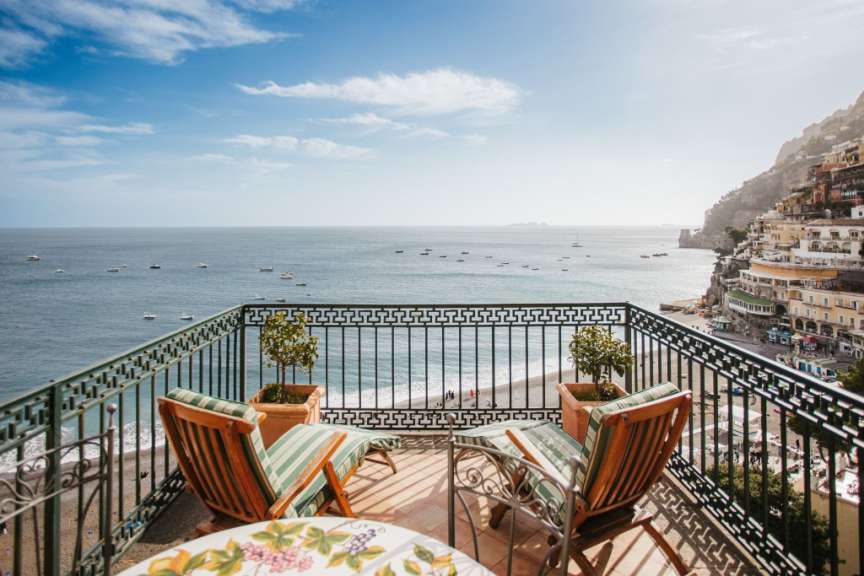 Ein Balkon mit zwei Stühlen und einem Tisch mit Blick auf das Meer