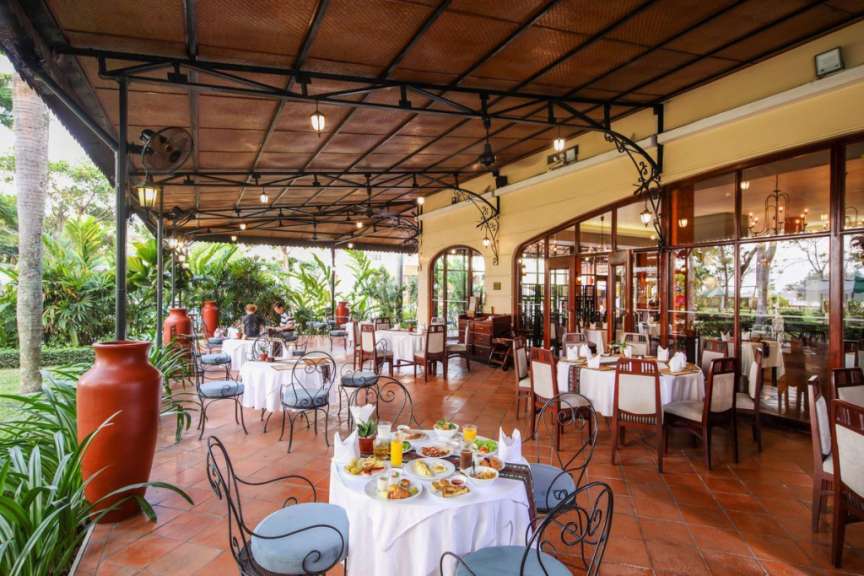 Die Aufnahme zeigt eine überdachte Terrasse mit Tischen und Stühlen, die zu einer Mahlzeit im Freien einladen.