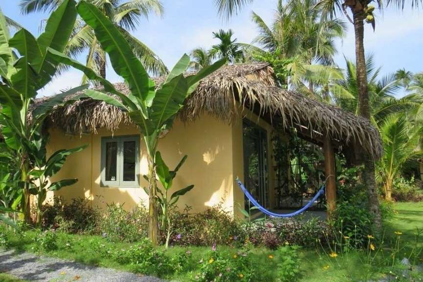 Ein Haus mit Strohdach und einer Hängematte davor