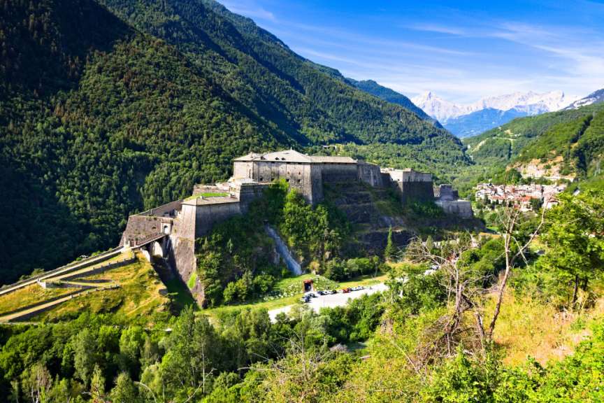 Ein großes Schloss sitzt auf einem Hügel inmitten einer Bergkette