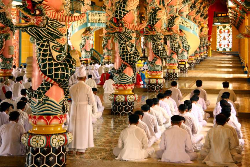 Eine Gruppe von Menschen sitzt in einem Tempel und betet
