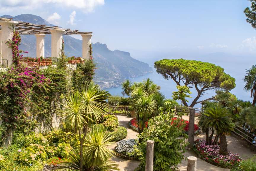 Ein Garten mit Palmen und Blumen mit Blick auf den Ozean