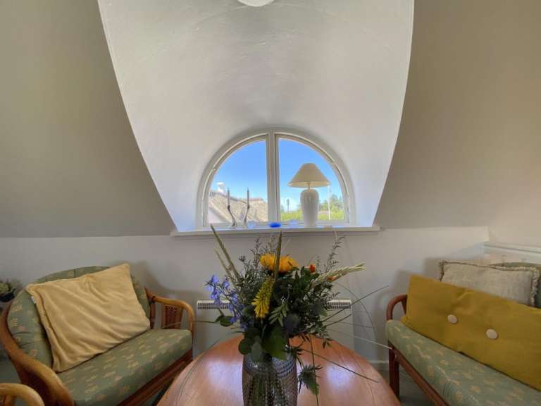 Eine Vase mit Blumen sitzt auf einem Tisch vor einem Fenster