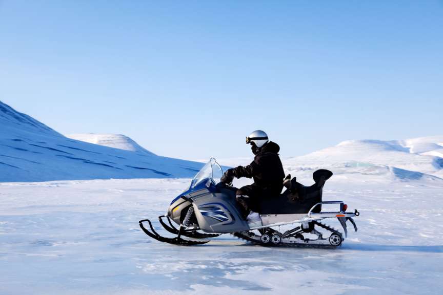 Ein Mann fährt mit einem Schneemobil auf einem schneebedeckten Feld