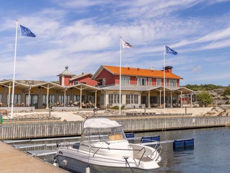 Ein kleines weißes Boot liegt vor einem roten Gebäude