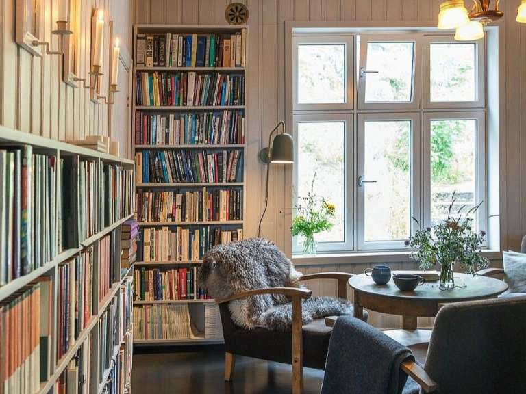 Ein Wohnzimmer mit Bücherregalen und einem Stuhl mit einer Decke darauf