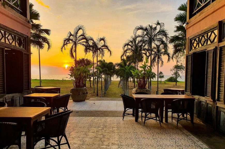Tische und Stühle auf einer Terrasse mit Blick auf das Meer bei Sonnenuntergang