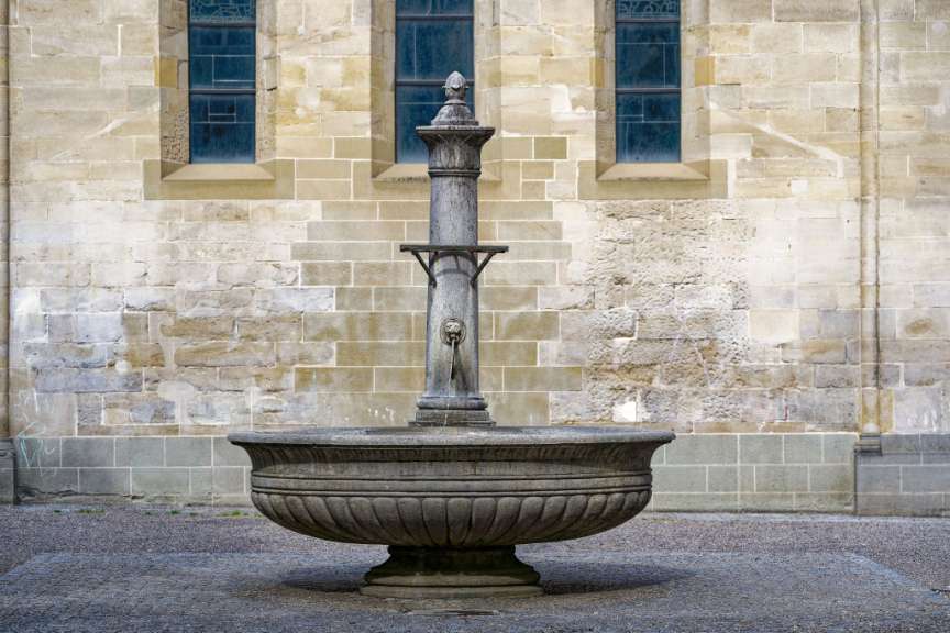 Ein Brunnen steht vor einer Backsteinmauer