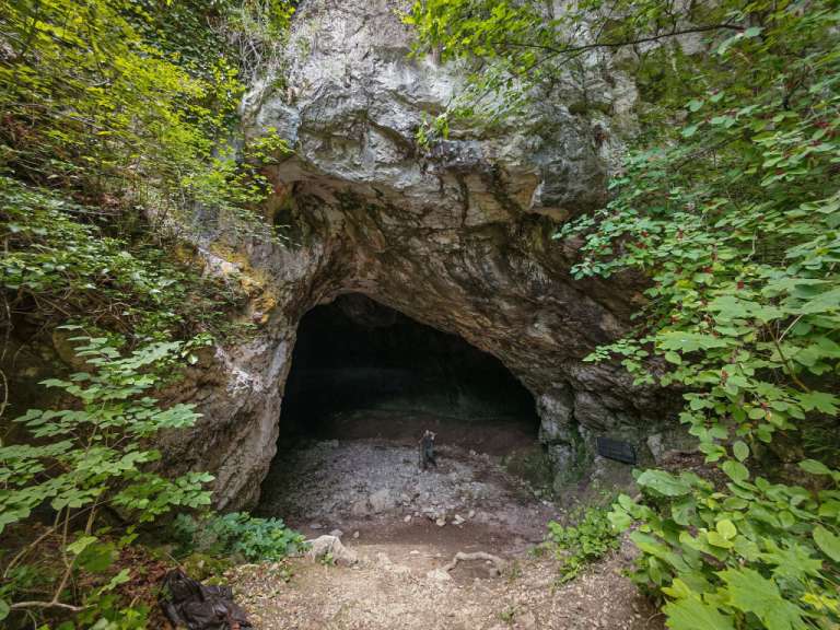 Ein Mann steht vor einer Höhle mit einem Schild davor