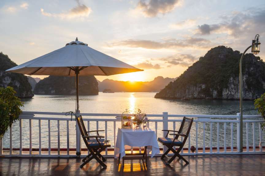 Ein Tisch und Stühle auf einem Deck mit Blick auf das Meer bei Sonnenuntergang