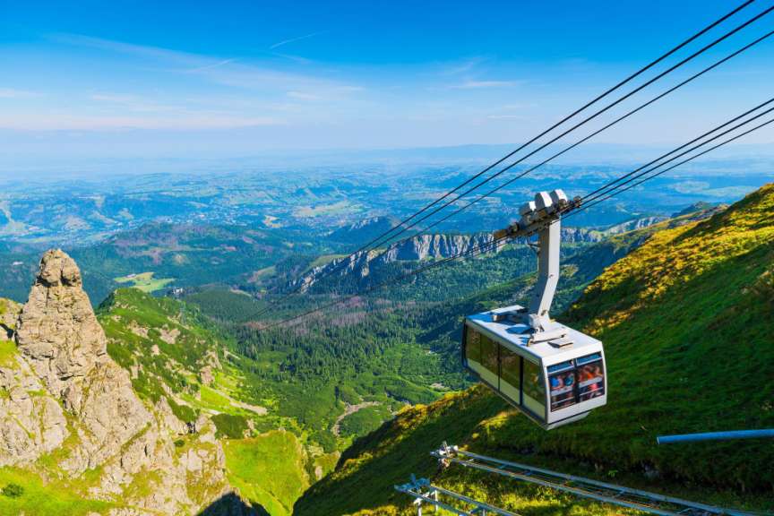 Eine Seilbahn fährt über eine grüne Bergkette