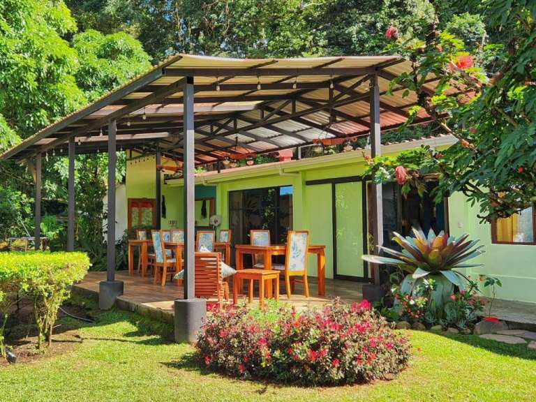 Ein grünes Haus mit einem Tisch und Stühlen davor