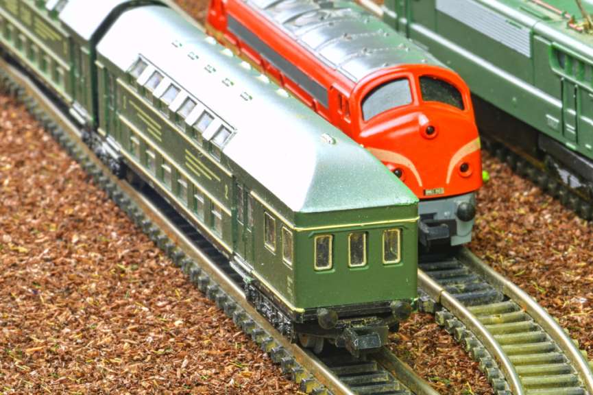 Ein grüner Wagen fährt neben einem roten Zug