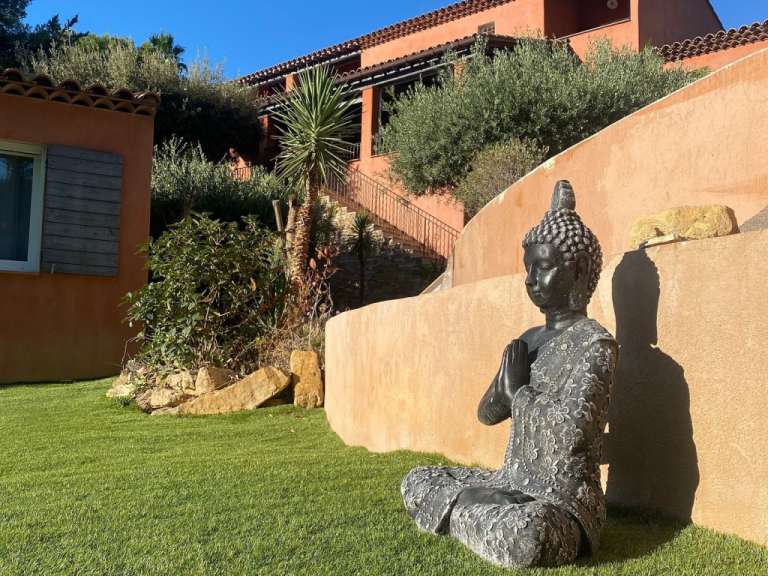 Eine Statue eines buddhas sitzt auf einem grünen Rasen