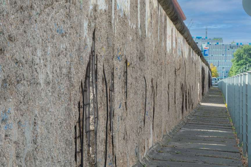 Eine sehr lange Wand mit einem Gebäude im Hintergrund mit einem blauen Schild darauf