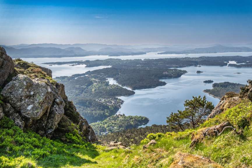 Eine weite Landschaft mit Bergen, einem Meer und üppiger Vegetation.