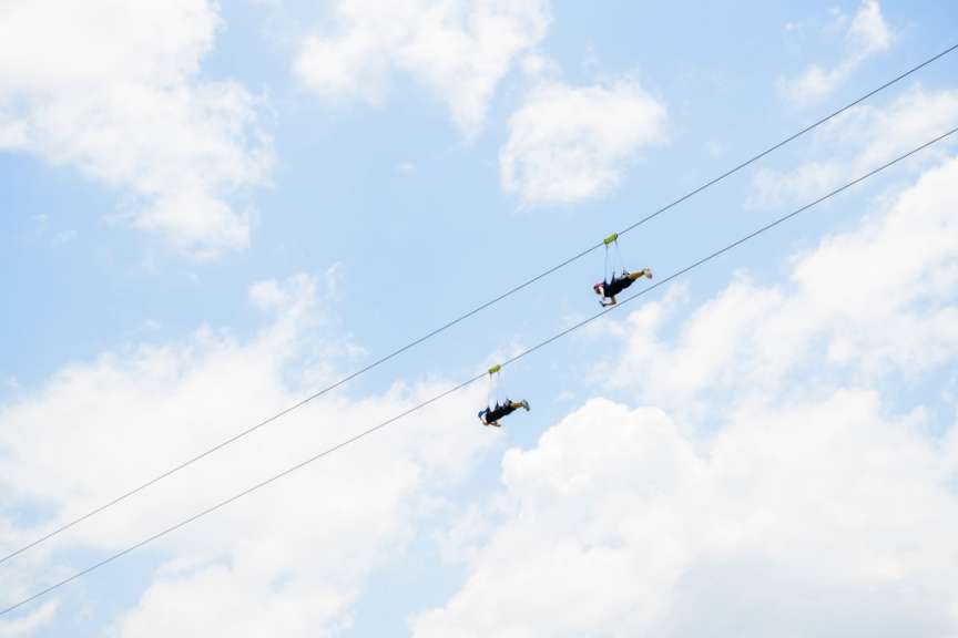 Zwei Menschen fliegen auf einer Seilbahn in den Himmel