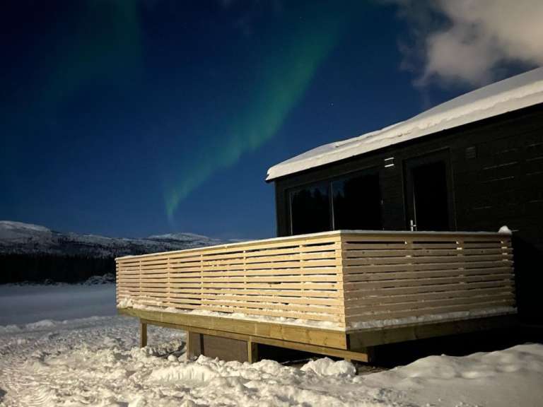 Das Nordlicht scheint über einem schneebedeckten Haus