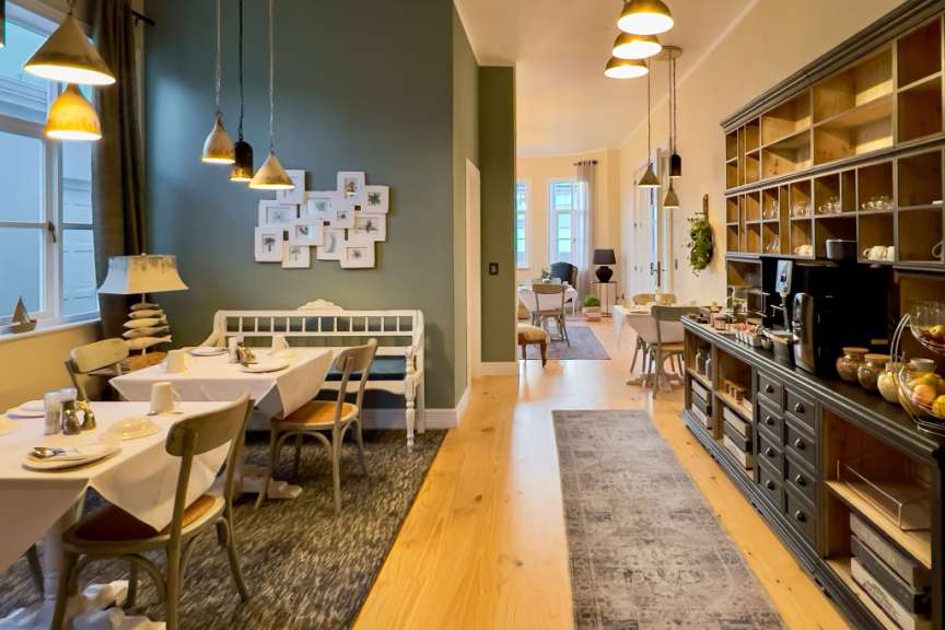 Ein Frühstücksraum mit mehreren Tischen, Stühlen, einem Buffet und einer Wanddekoration.