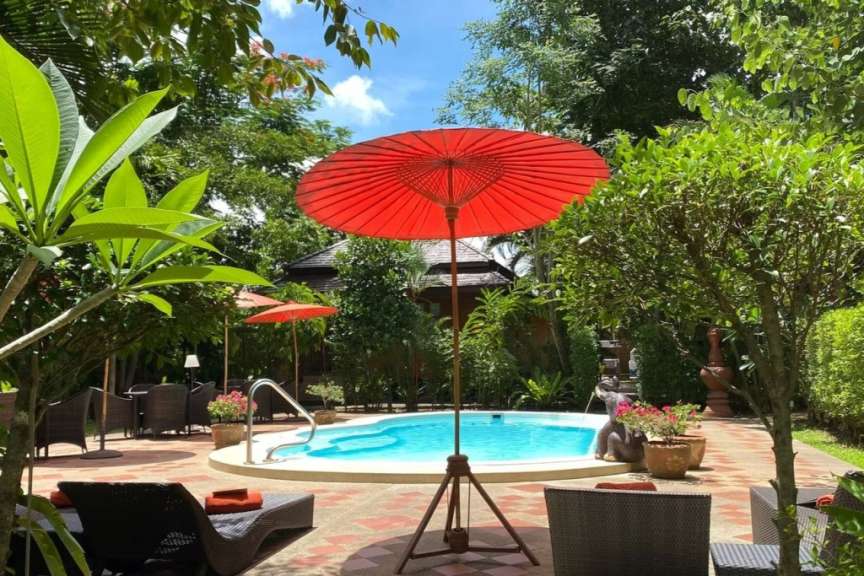 Ein großer roter Regenschirm steht vor einem Swimmingpool