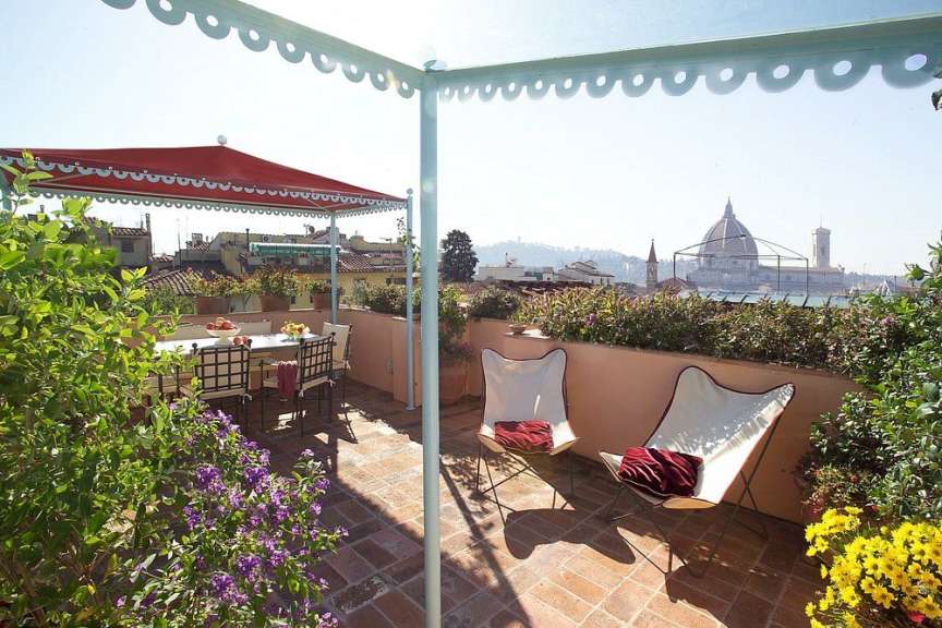 Eine Terrasse mit Tisch und Stühlen und einem roten Regenschirm