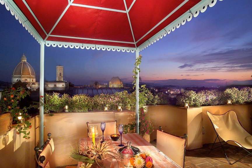 Eine Terrasse mit einem Tisch und Stühlen und einem roten Zelt