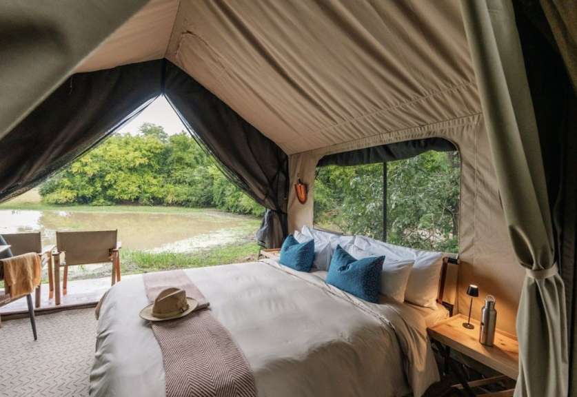 Ein Bett in einem Zelt mit Blick auf einen Fluss