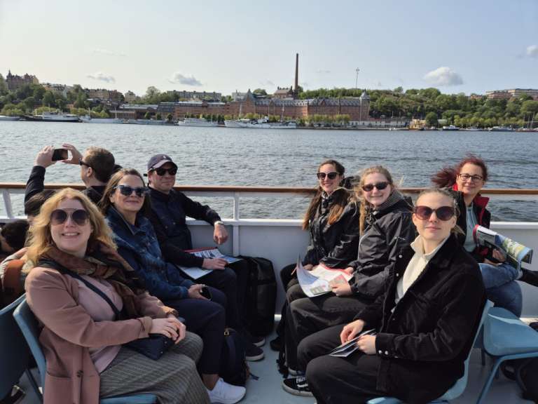 Eine Gruppe von Menschen sitzt auf einem Boot und schaut auf das Wasser