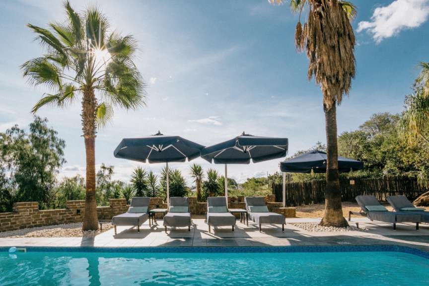Liegestühle und Sonnenschirme um einen Swimmingpool an einem sonnigen Tag
