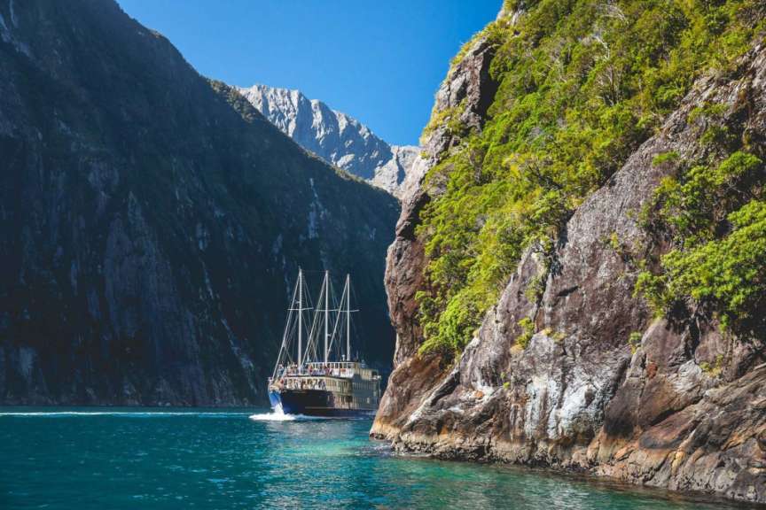 Ein Boot fährt durch einen Fjord mit Bergen im Hintergrund