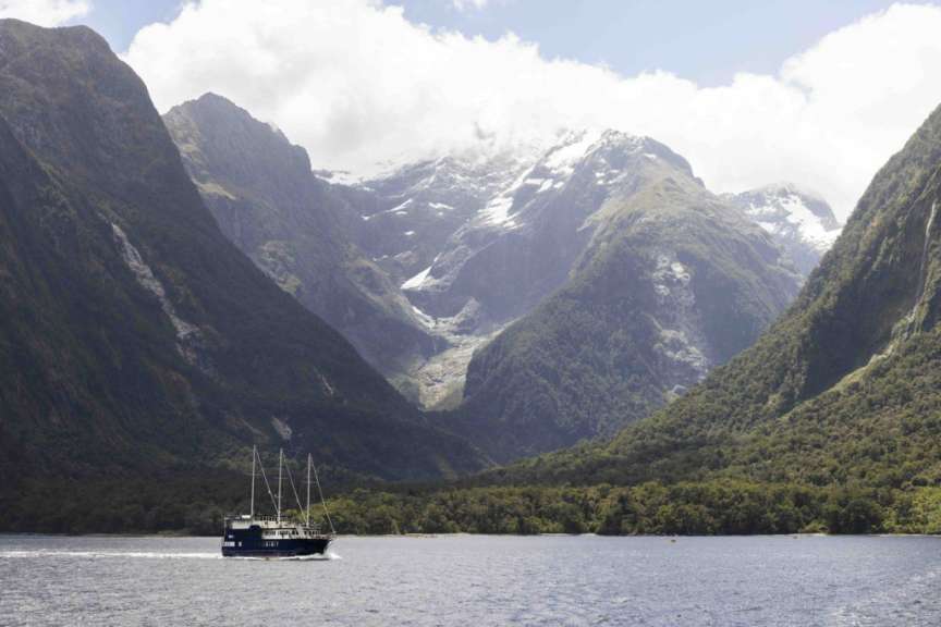 Ein Boot fährt durch einen See mit Bergen im Hintergrund