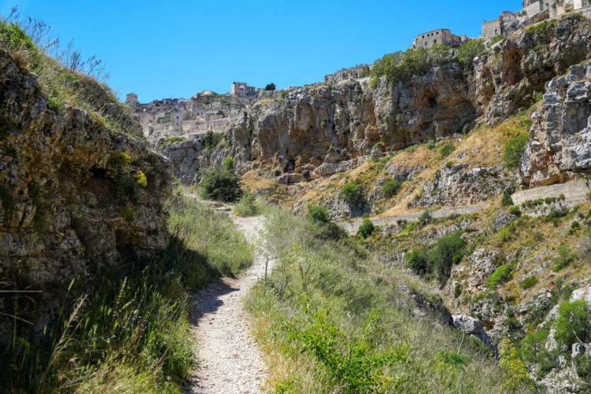 Ein Schotterweg führt durch eine Felswand in eine Stadt