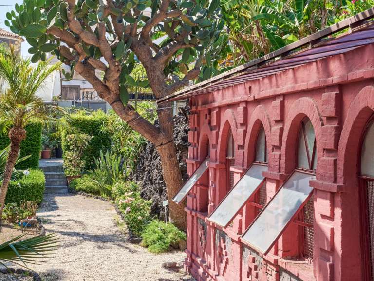 Ein rosa Gebäude mit vielen Fenstern und einem Baum davor