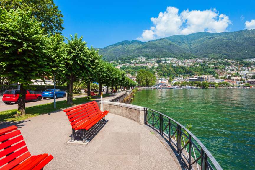 Eine rote Bank sitzt auf einem Bürgersteig neben einem See