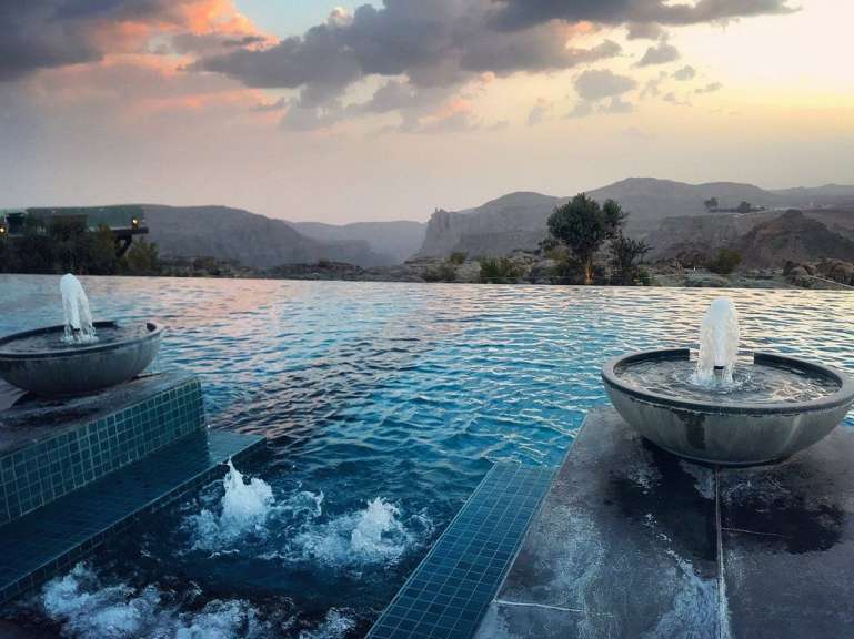 Ein Infinity-Pool mit zwei Brunnen und einem Berg im Hintergrund