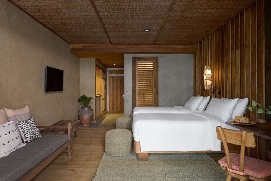 Dieses Bild zeigt ein Schlafzimmer mit zwei Betten, einem Sofa, einem Fernseher und Holzakzenten.