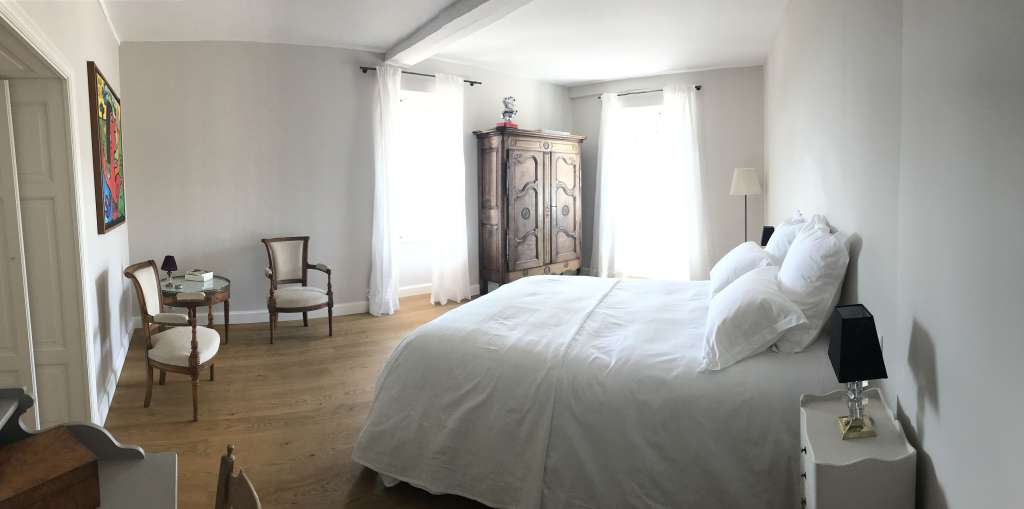 Ein luxuriös eingerichtetes Schlafzimmer mit einem Himmelbett, einem alten Kleiderschrank und einem bemalten Wandbild.