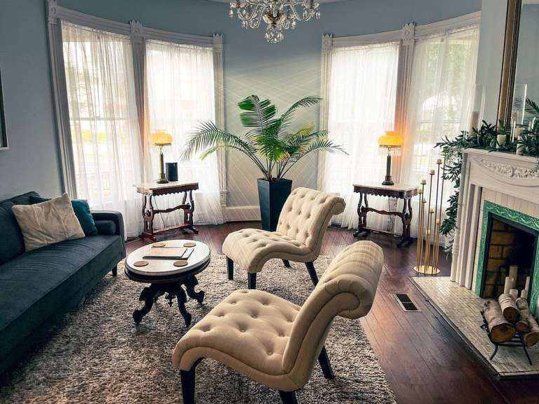 Ein Wohnzimmer mit Couch, Stühlen, Tisch und Kamin