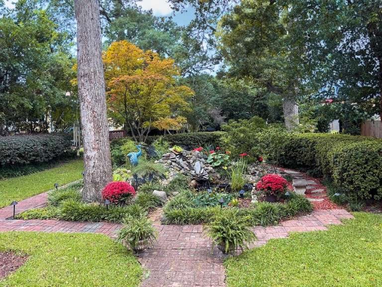 Ein Garten mit einem Brunnen und roten Blumen