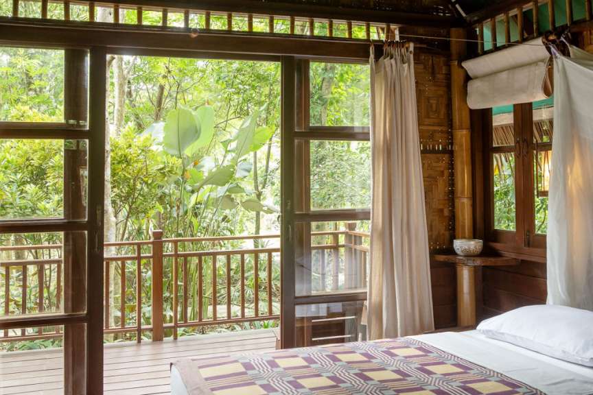 Ein Schlafzimmer mit einem Bett und einem Balkon mit Blick auf den Dschungel