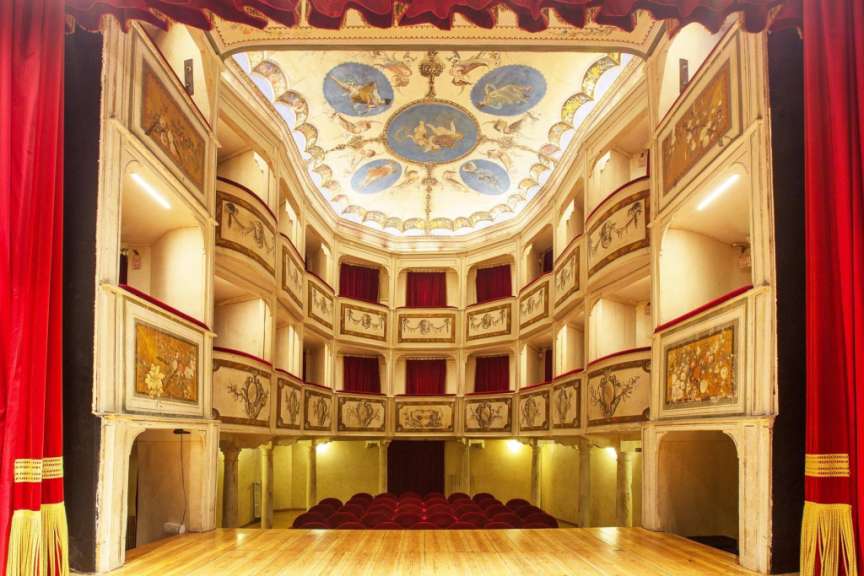 Ein Theater mit rotem Vorhang und einem Gemälde an der Decke