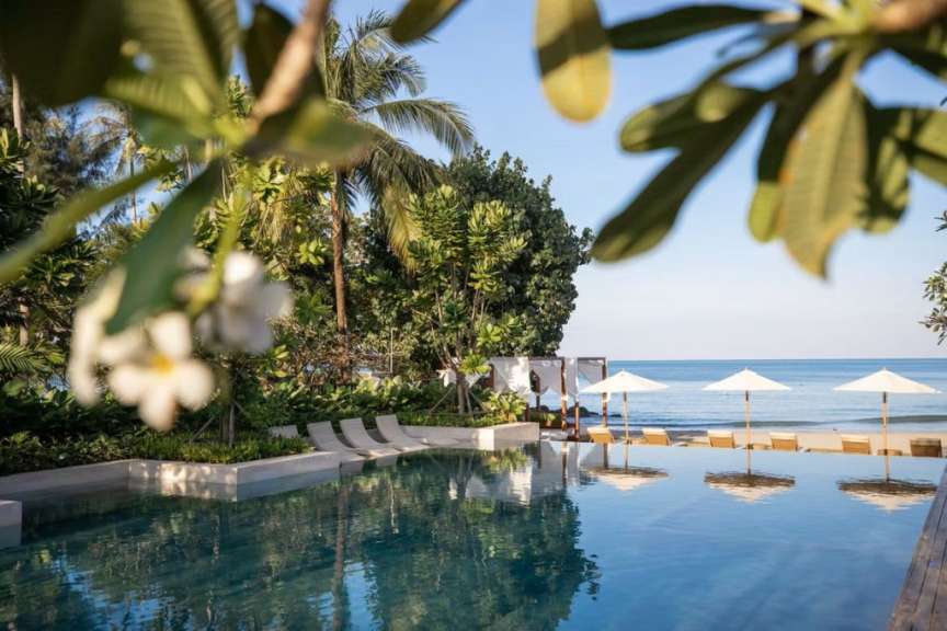 Ein Infinity-Pool mit Liegestühlen und Sonnenschirmen am Strand