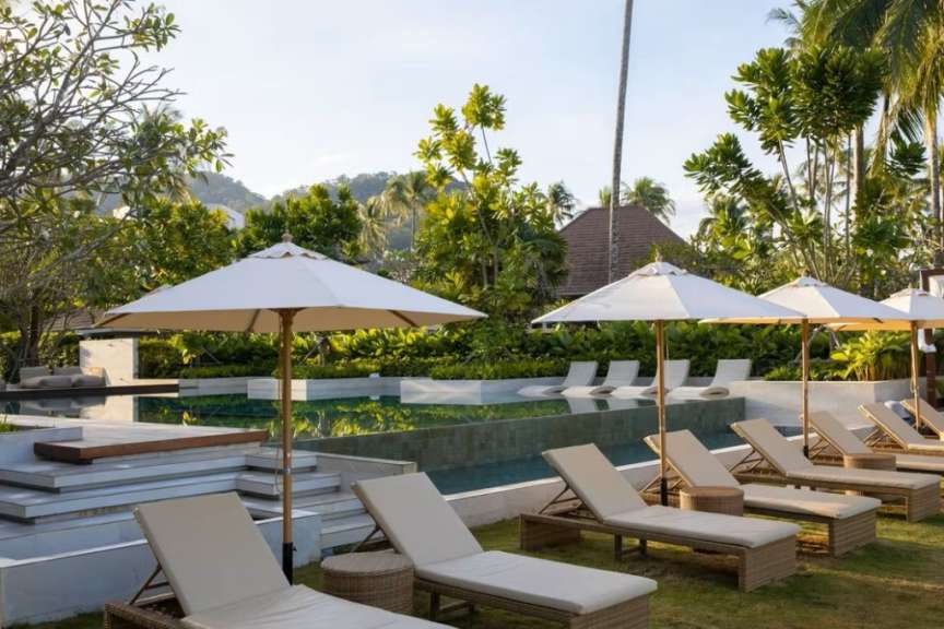Liegestühle und Sonnenschirme stehen neben einem Pool
