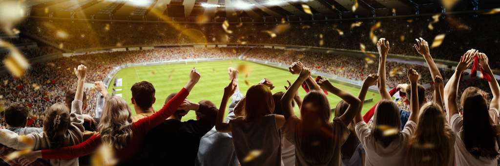 Eine Gruppe von Menschen hält ihre Hände in die Luft, während sie ein Fußballspiel sehen