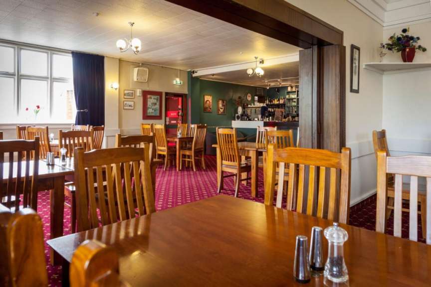 Ein Restaurant mit Holztischen und Stühlen und einem roten Teppich